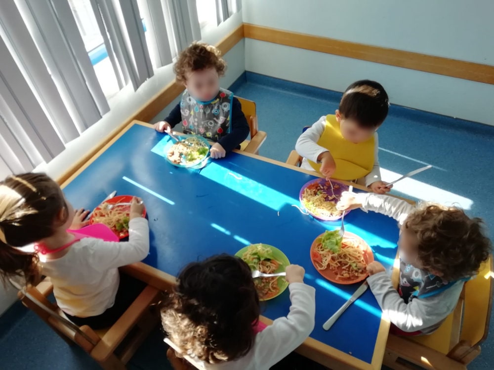 5 crianças à mesa a almoçar de forma independente.